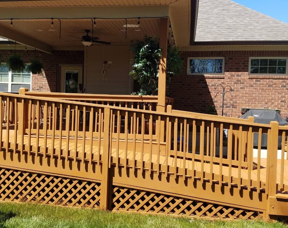 Freshly cleaned and stained wooden deck and accessibility ramp on a brick home